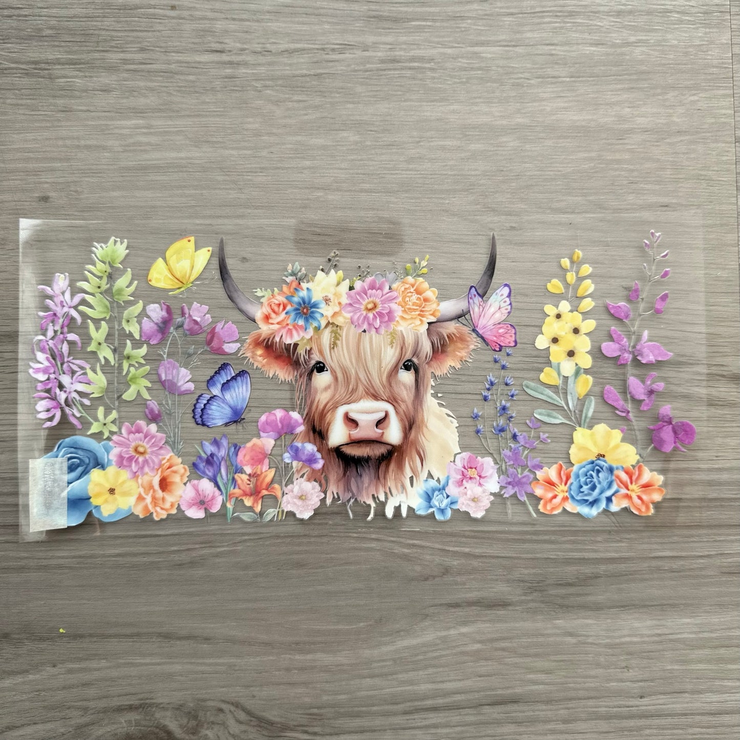 A Highland cow with floral decoration around it, and its wearing a floral headband.