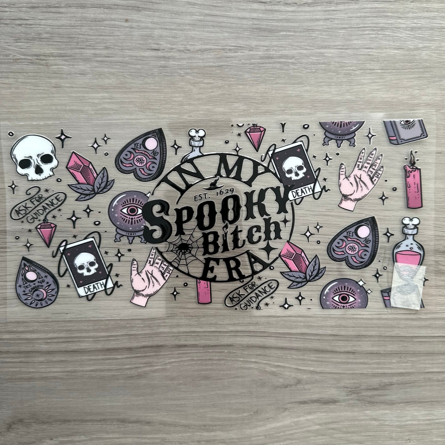 "In My Spooky Bitch Era" with the death tarot card, candles, a planchette, crystals, with like a spooky vibe. 