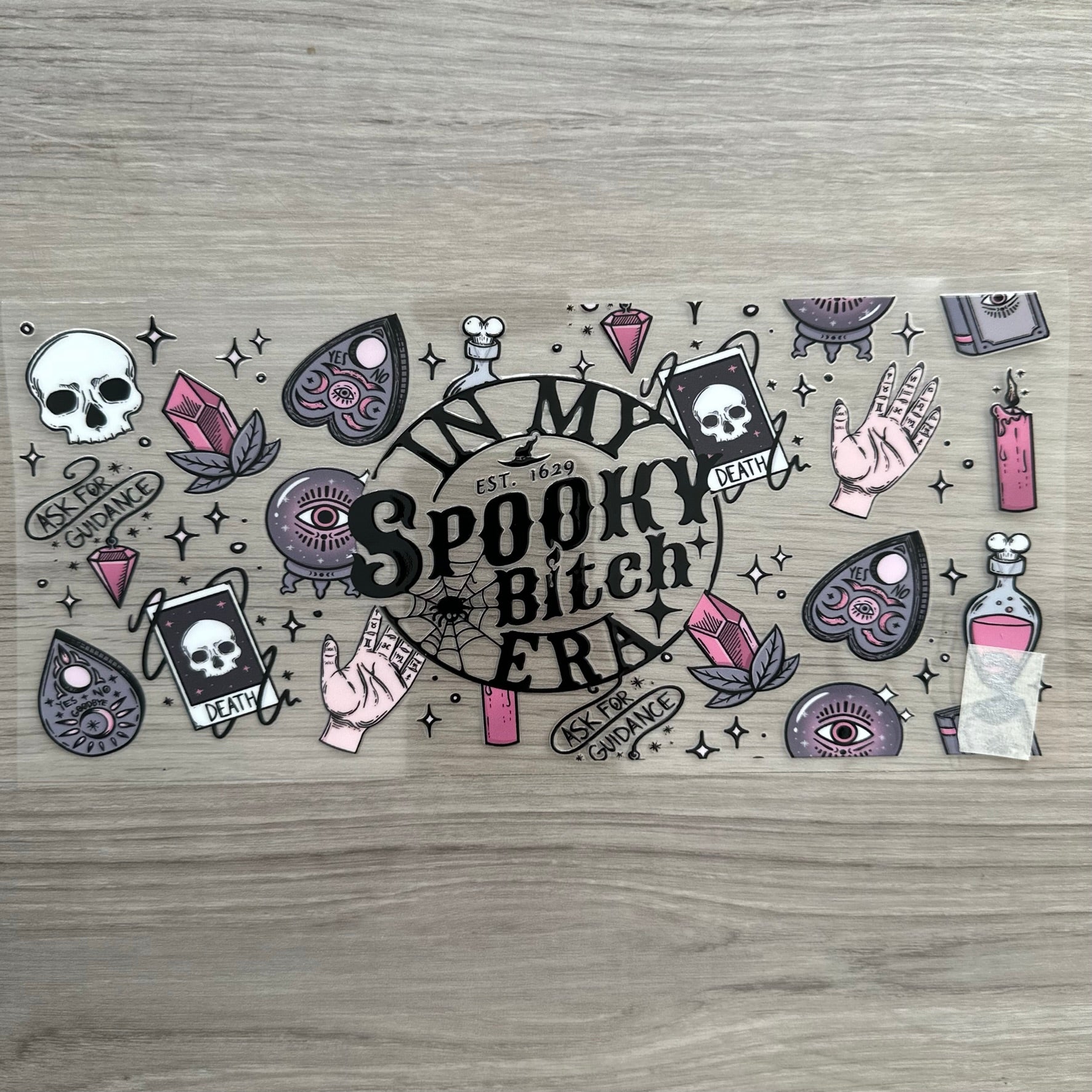 "In My Spooky Bitch Era" with the death tarot card, candles, a planchette, crystals, with like a spooky vibe. 